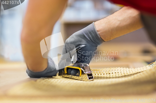 Image of assembler with staple gun making furniture