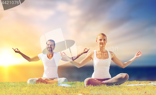 Image of happy couple making yoga and meditating outdoors