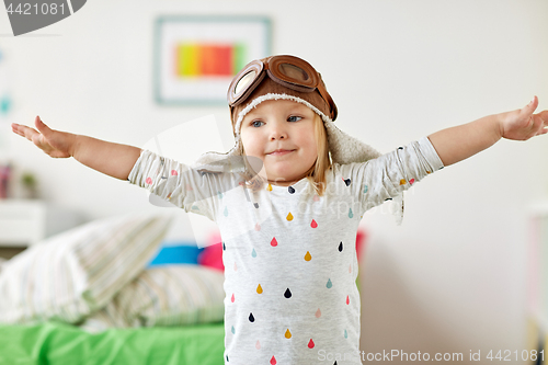 Image of happy little girl in pilot hat playing at home