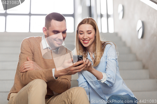 Image of man and woman with smartphone at office stairs
