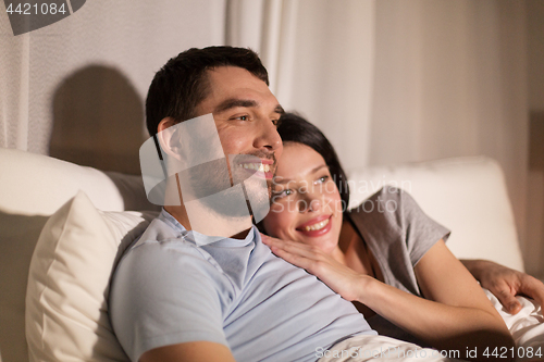Image of happy couple watching tv in bed at night at home