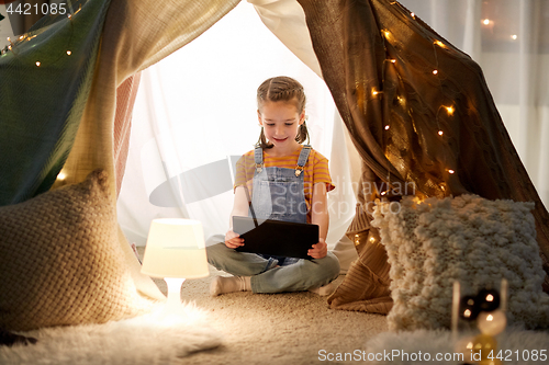 Image of little girl with tablet pc in kids tent at home