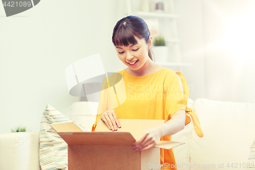 Image of happy asian young woman with parcel box at home