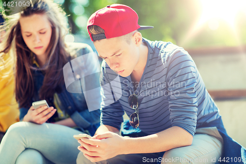 Image of teenage friends with smartphones outdoors