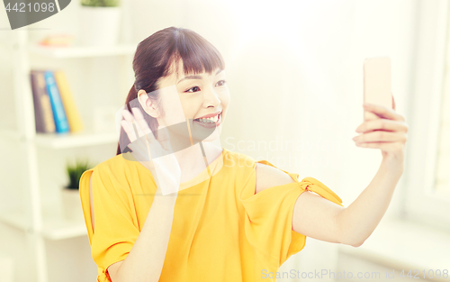Image of happy asian woman taking selfie with smartphone