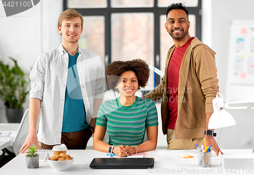 Image of happy creative team with laptop at office