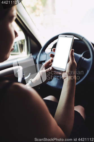 Image of Woman looking at the screen of the smartphone in the car