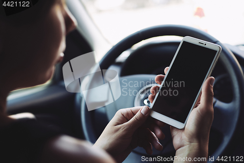 Image of Woman looking at the screen of the smartphone in the car