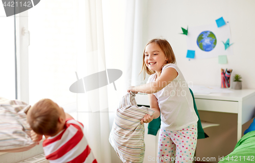 Image of kids playing and fighting by pillows at home