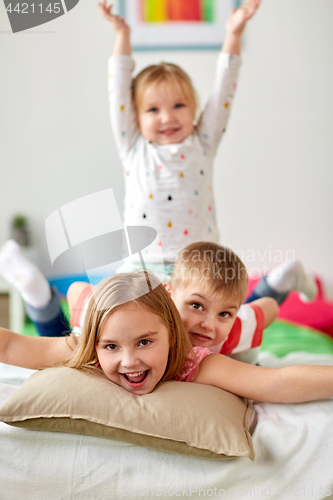 Image of happy little kids having fun in bed at home