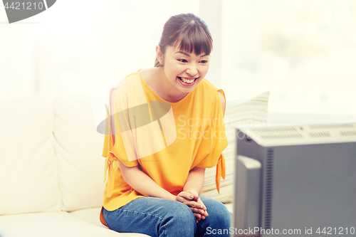 Image of happy asian young woman watching tv at home