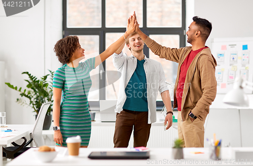 Image of happy creative team making high five at office