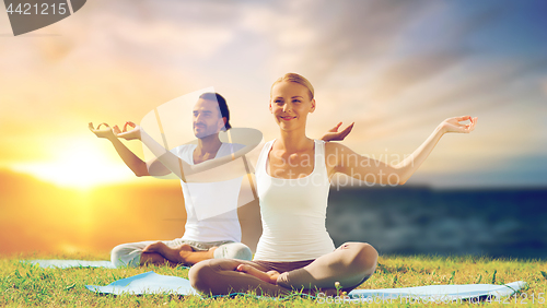 Image of happy couple making yoga and meditating outdoors