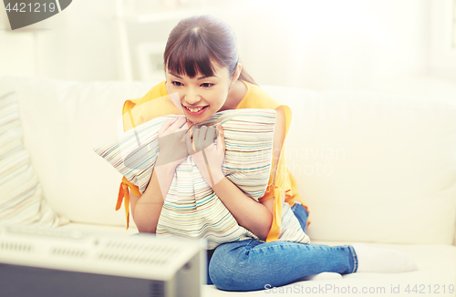 Image of happy asian young woman watching tv at home