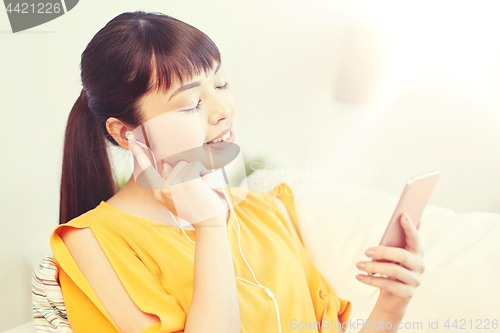 Image of happy asian woman with smartphone and earphones