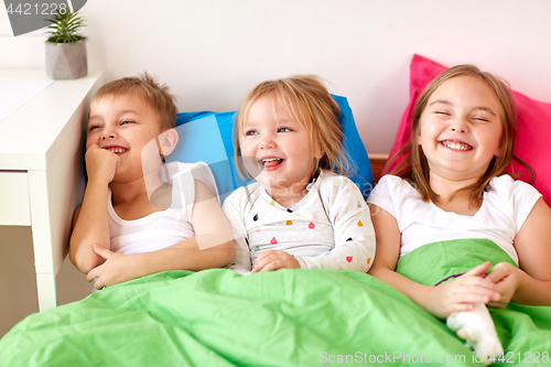 Image of happy little kids having fun in bed at home