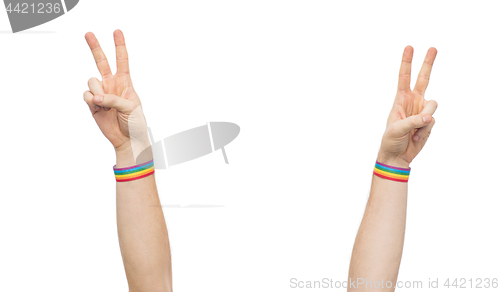 Image of hands with gay pride rainbow wristbands make peace