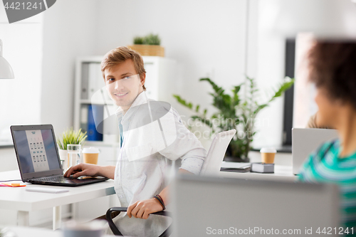 Image of happy creative workers with laptops at office