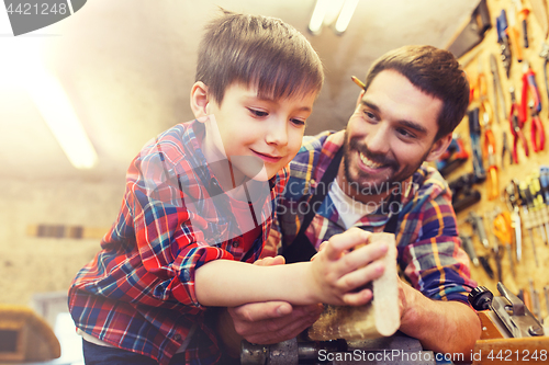 Image of father and little son with wood plank at workshop