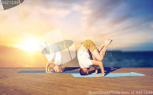 Image of couple doing yoga headstand outdoors