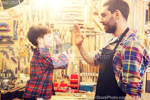 Image of father and little son making high five at workshop