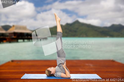 Image of woman making yoga in shoulderstand pose outdoors
