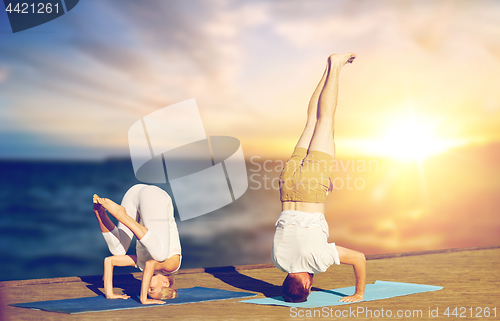 Image of couple doing yoga headstand outdoors