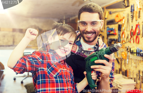 Image of father and son with drill working at workshop