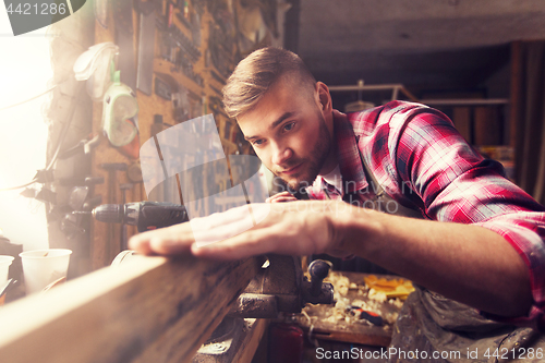 Image of carpenter working with wood plank at workshop