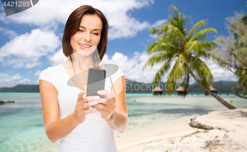 Image of woman taking selfie by smartphone on beach