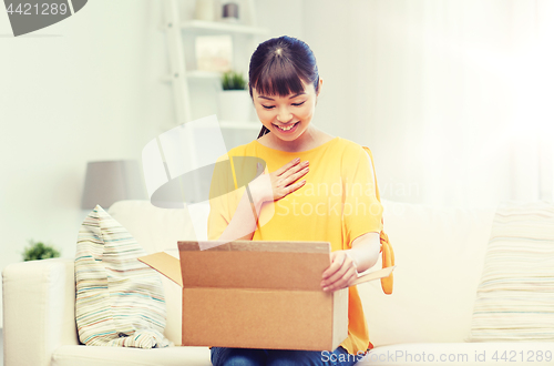 Image of happy asian young woman with parcel box at home