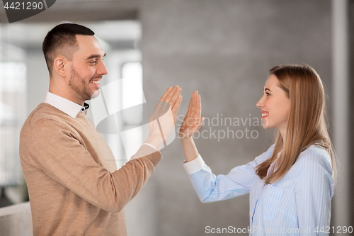Image of man and woman making high five at office