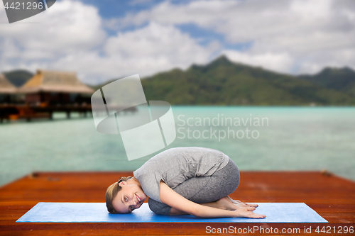 Image of happy woman making yoga in child pose outdoors