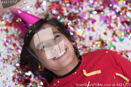 Image of kid blowing confetti while lying on the floor