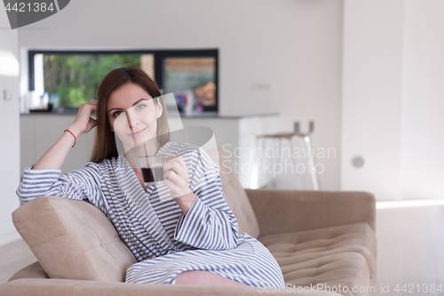 Image of young woman in a bathrobe enjoying morning coffee