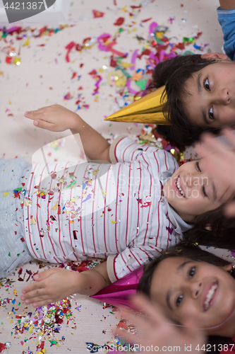 Image of kids  blowing confetti while lying on the floor