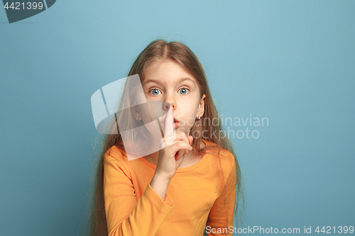 Image of The call for silence. Teen girl on a blue background. Facial expressions and people emotions concept