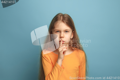 Image of The call for silence. Teen girl on a blue background. Facial expressions and people emotions concept