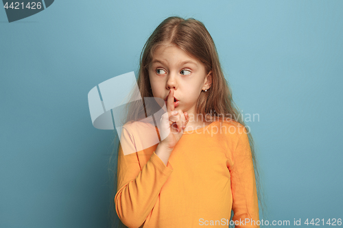 Image of The call for silence. Teen girl on a blue background. Facial expressions and people emotions concept