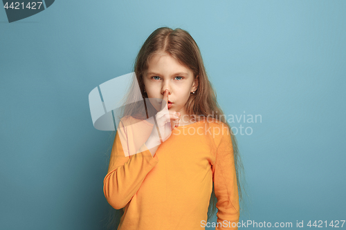 Image of The call for silence. Teen girl on a blue background. Facial expressions and people emotions concept