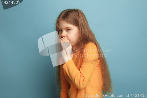 Image of The secret. The teen girl on a blue studio background. Facial expressions and people emotions concept.