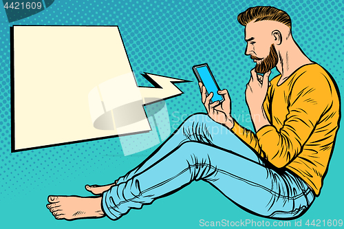 Image of Hipster man sitting on the floor and reading smartphone