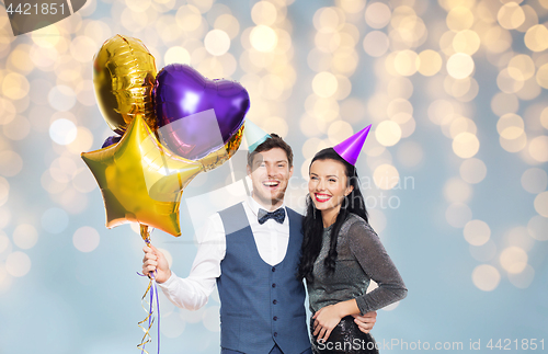 Image of couple with party caps and balloons over lights