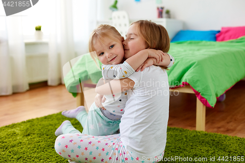 Image of happy little girls or sisters hugging at home