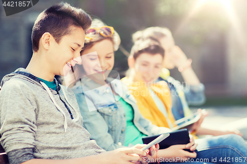 Image of happy teenage friends with tablet pc outdoors