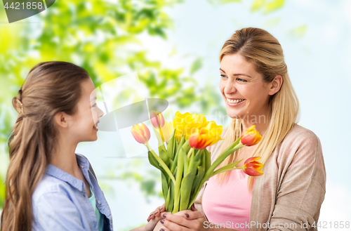 Image of happy daughter giving flowers to mother