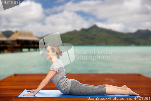 Image of woman making yoga in dog pose on mat outdoors