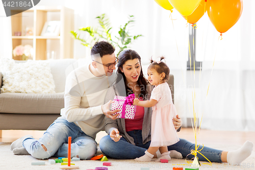 Image of baby girl with birthday gift and parents at home 