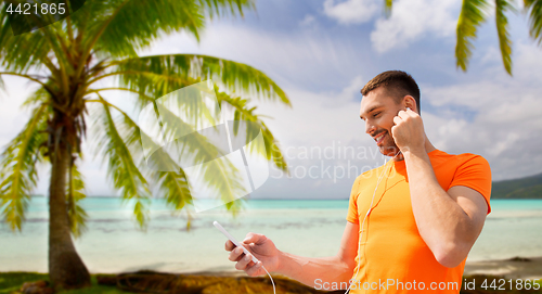 Image of man with smartphone and earphones over beach