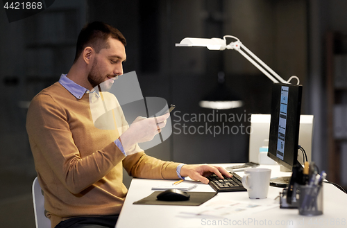 Image of man with smartphone working late at night office